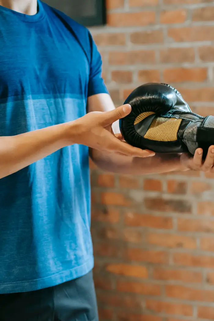 Un coach à Saint Mathieu De Tréviers, en train d'aider son élève à mettre ses gants de boxe, bienveillance et confiance