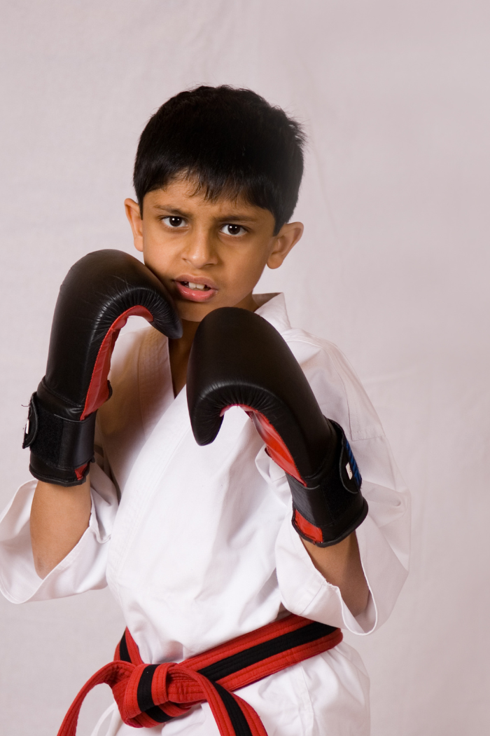 Un enfant en kimono avec les gants qui est en garde et confiant