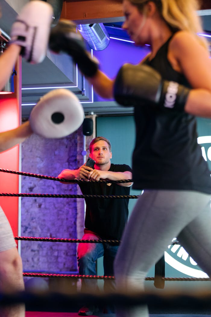 Une boxeuse qui s'entraine avec une autre en frappant sur des cibles sous le regard expert d'un coach